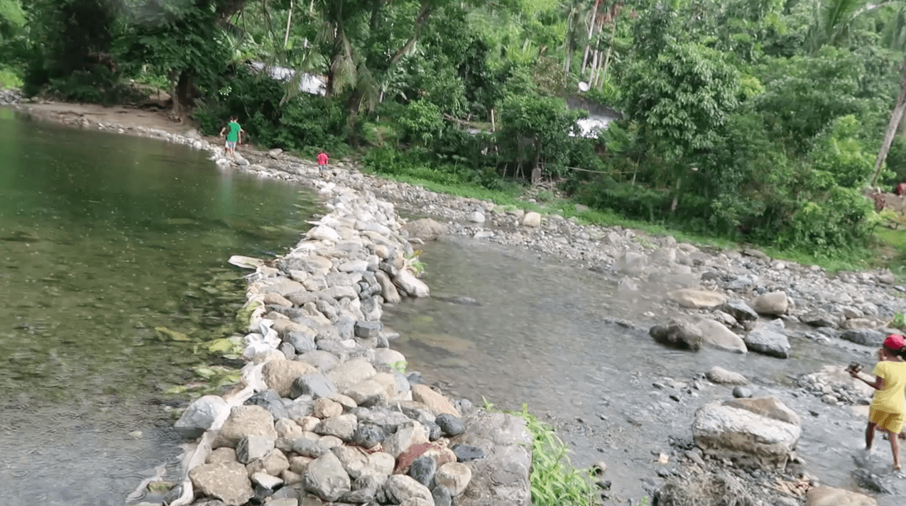 rocky river with filipino kids walking through water in catanduanes province philippines